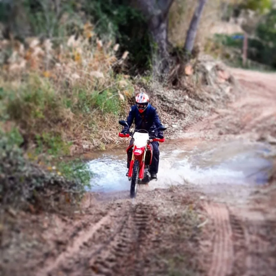 Rider crossing a shallow river ford on a Honda CRF250L trail bike in Catalonia